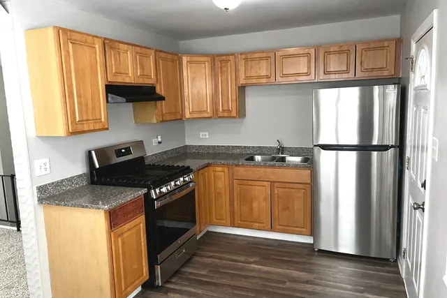 a kitchen with granite countertop a refrigerator a sink and wooden cabinets