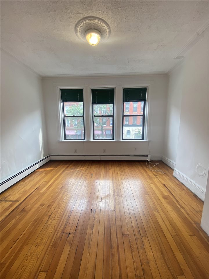 112 14th Street, Unit 7 Hoboken, NJ 07030 - Photo 4 of 8 an empty room with wooden floor and windows