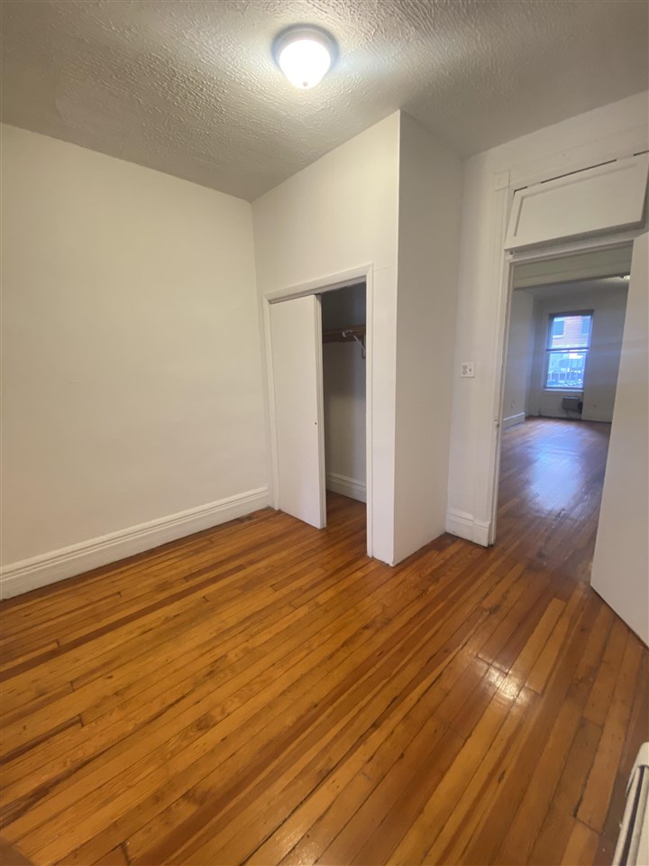 112 14th Street, Unit 7 Hoboken, NJ 07030 - Photo 6 of 8 a view of an empty room with wooden floor and a window