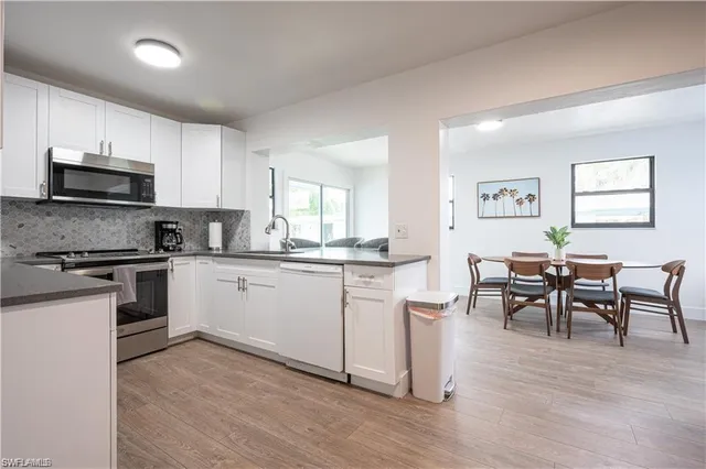 a kitchen with stainless steel appliances granite countertop a stove top oven a sink a dining table and chairs with wooden floor