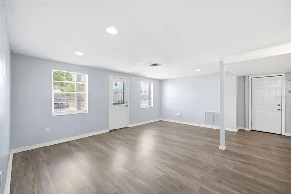 a view of an empty room with wooden floor and a window