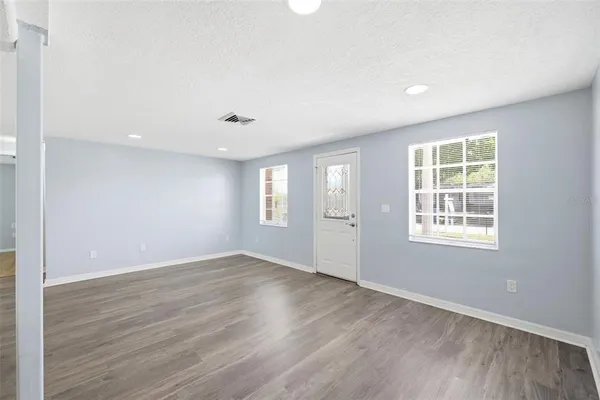 a view of an empty room with wooden floor and a window