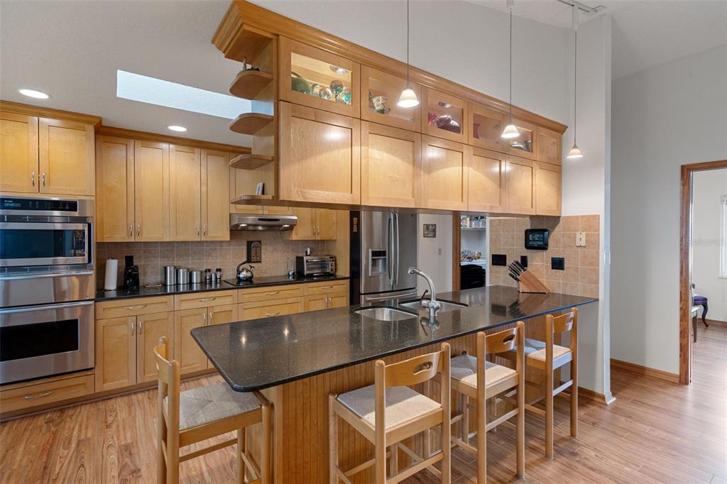 5035 Harbinger Road Spring Hill, FL 34608 - Photo 20 of 47 a kitchen with stainless steel appliances granite countertop a stove top oven a sink a refrigerator white cabinets and wooden floor