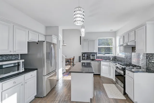a kitchen with stainless steel appliances granite countertop a refrigerator a stove a sink dishwasher a oven with white cabinets and wooden floor