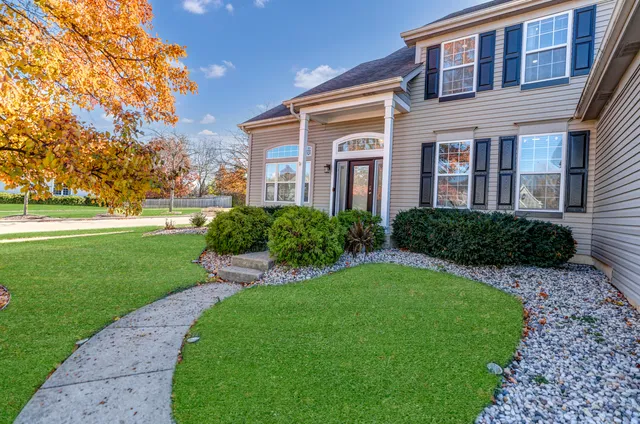 a front view of a house with garden and trees