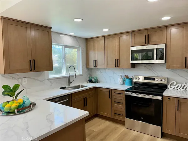 a kitchen with stainless steel appliances a stove a sink a microwave a refrigerator and cabinets