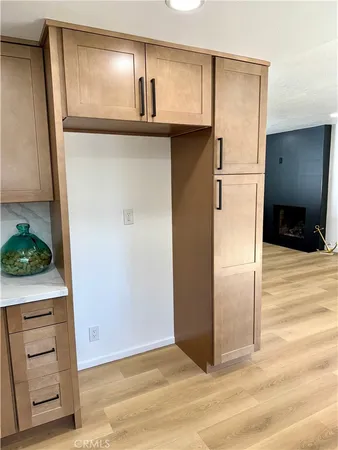 a view of a refrigerator in kitchen and an empty room with wooden floor