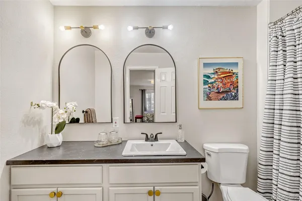 a bathroom with a granite countertop toilet a sink and a mirror