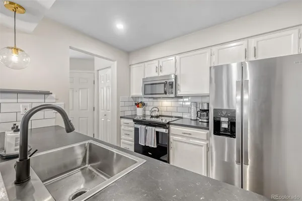 a kitchen with stainless steel appliances granite countertop a refrigerator a stove a sink and a microwave