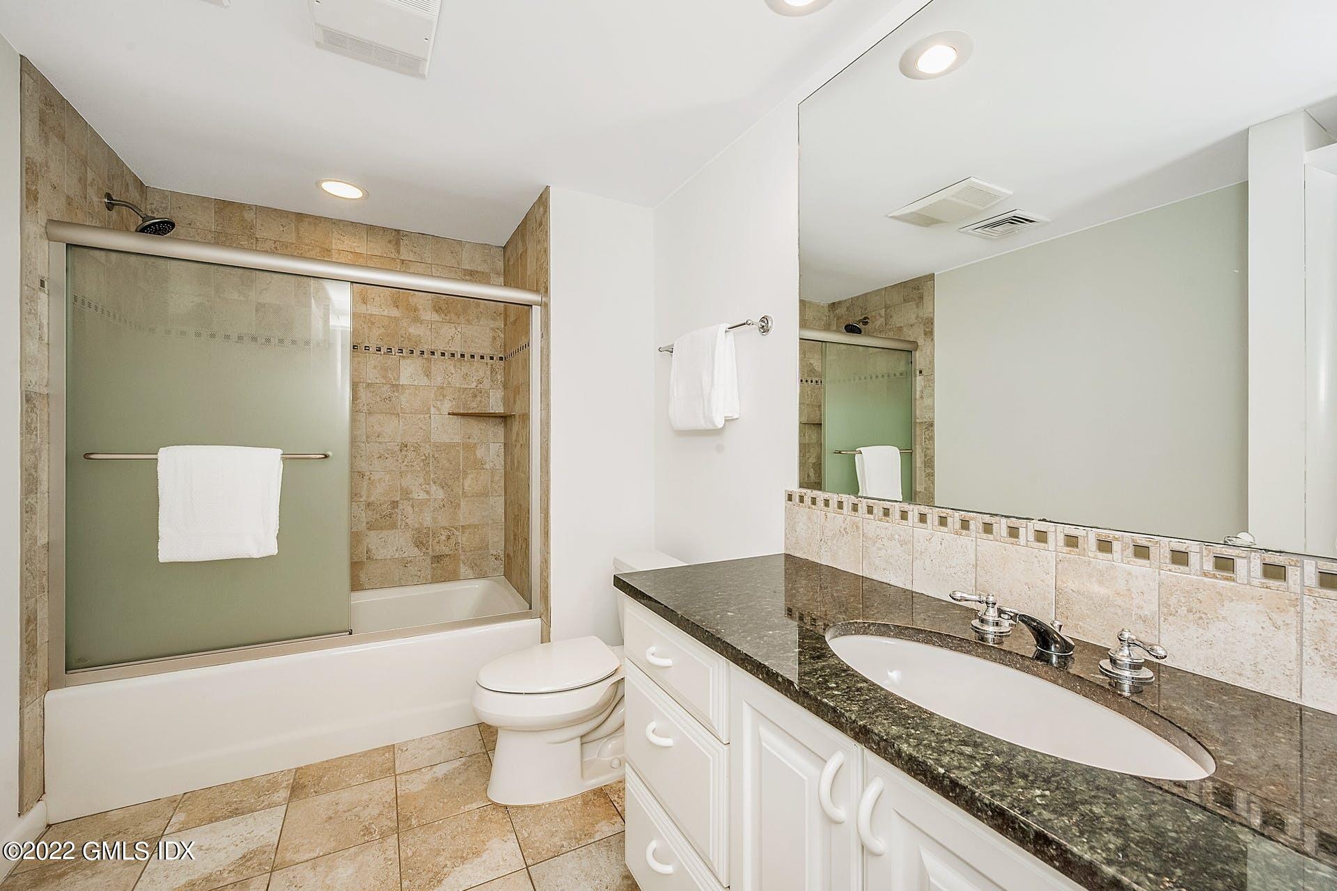 48 Valleywood Road Cos Cob, CT 06830 - Photo 17 of 25 a bathroom with a granite countertop sink a toilet a mirror and shower