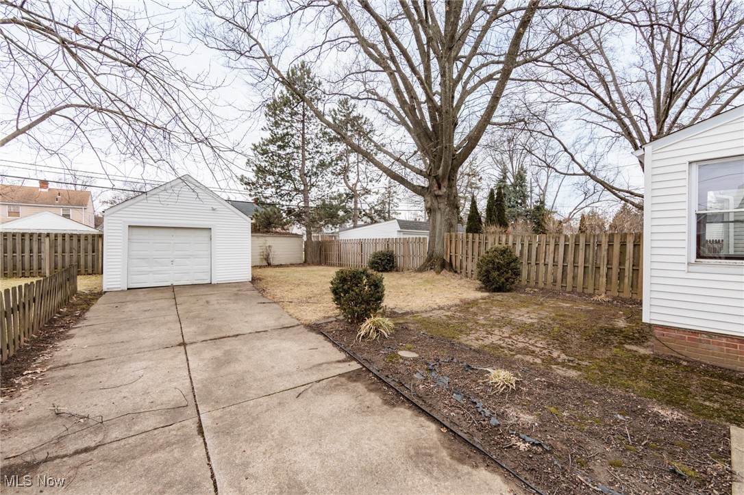 1232 Avondale Road Cleveland, OH 44121 - Photo 43 of 46 View of yard featuring an outbuilding, concrete driveway, a detached garage, and fence private yard