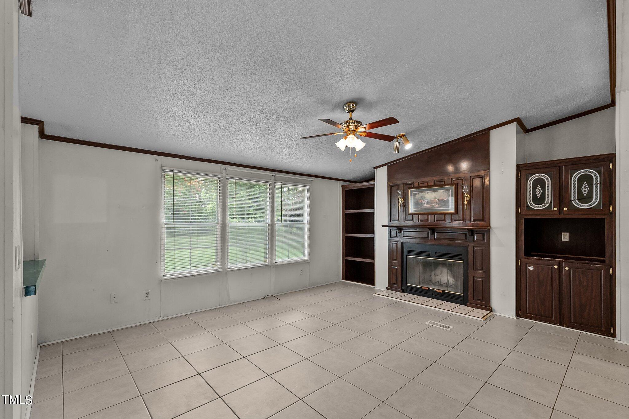 5612 Zacks Mill Road Angier, NC 27501 - Photo 13 of 42 a view of an empty room with a fireplace and a window