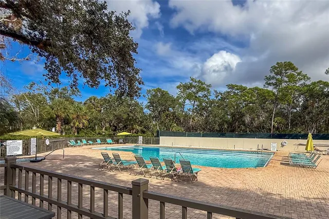 a view of a swimming pool with a yard and palm trees
