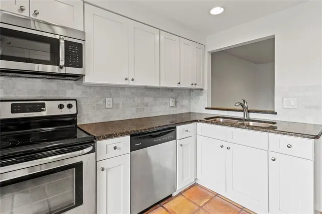 a kitchen with granite countertop white cabinets and stainless steel appliances