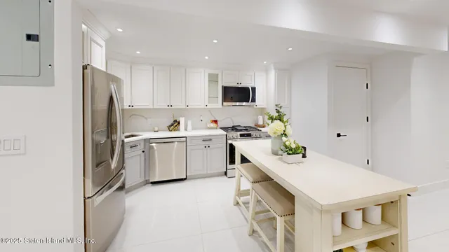 a kitchen with a sink a stove a refrigerator and white cabinets