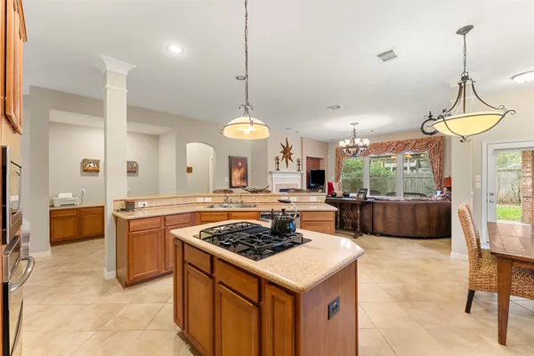a kitchen with a stove a sink a counter top space and living room view