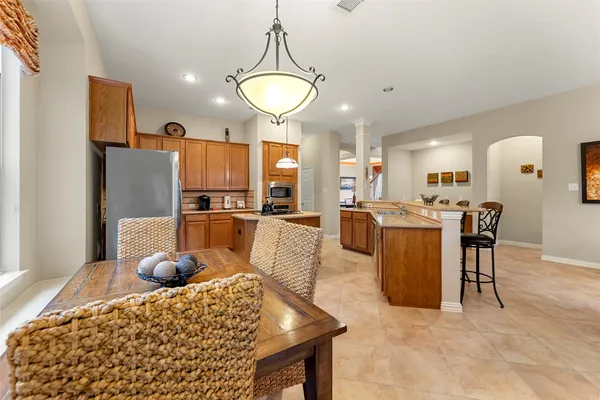 a kitchen with stainless steel appliances granite countertop a sink a stove a refrigerator cabinets and chairs