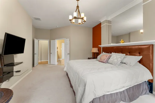 a bedroom with a bed and a flat tv screen on dresser