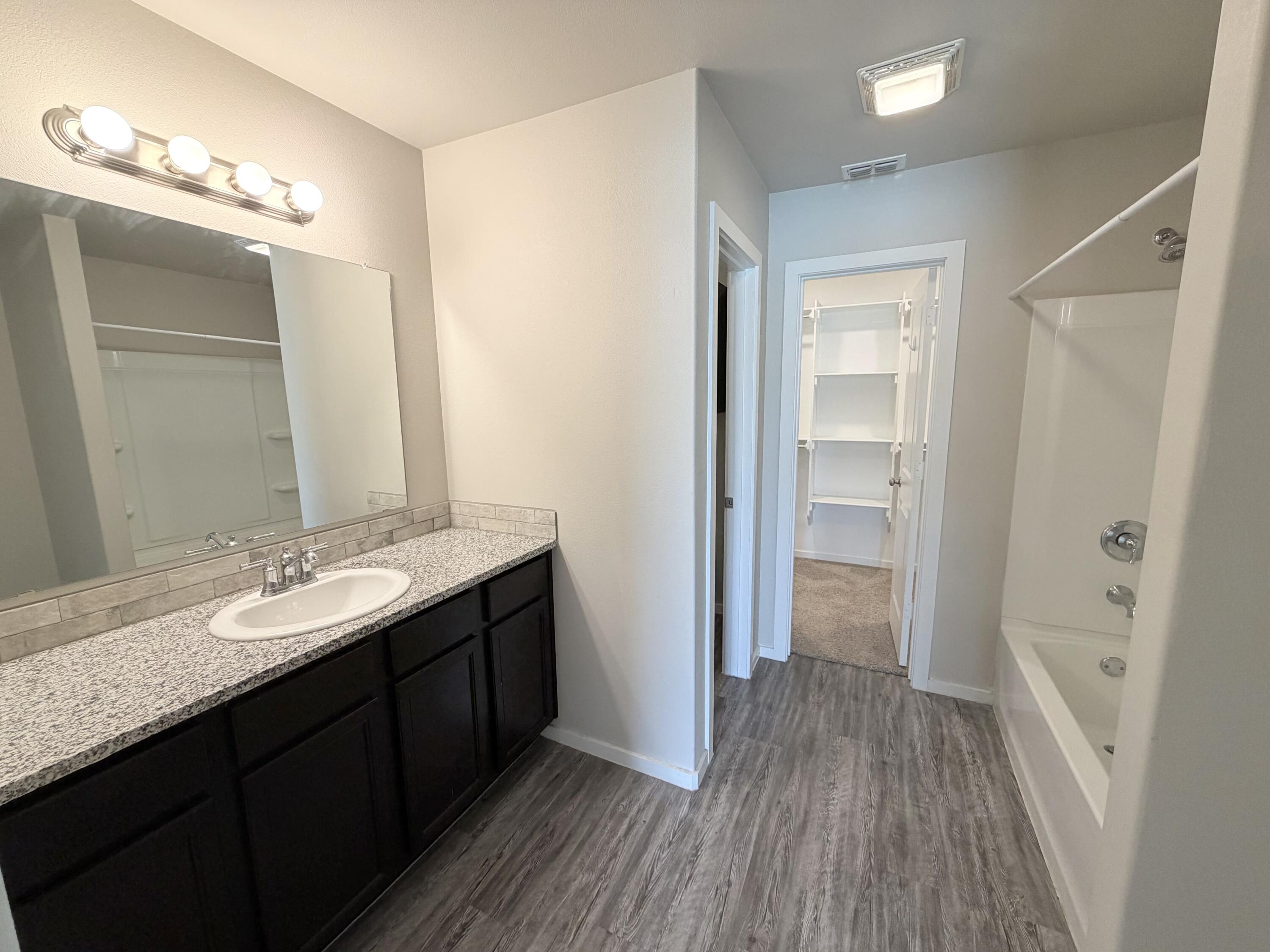1619 133rd Street, Unit B Lubbock, TX 79423 - Photo 14 of 24 a bathroom with a sink a mirror and a shower