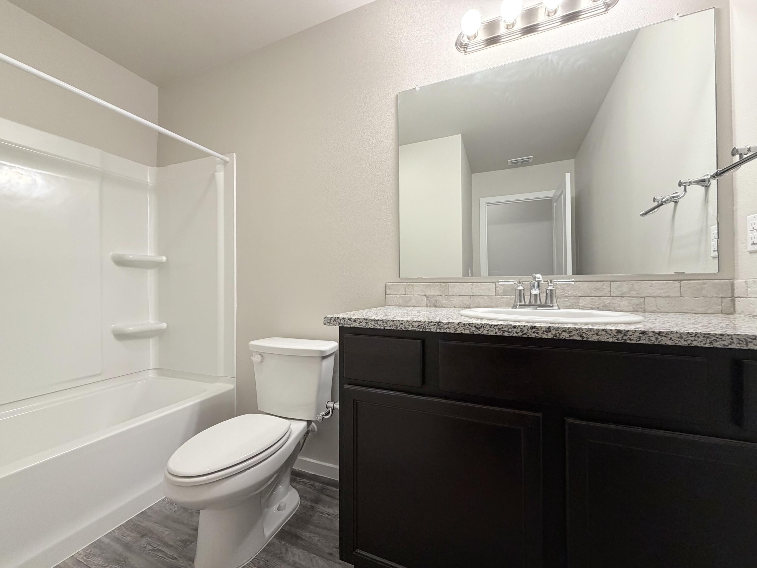 1619 133rd Street, Unit B Lubbock, TX 79423 - Photo 9 of 24 a bathroom with a granite countertop sink toilet a large mirror and shower