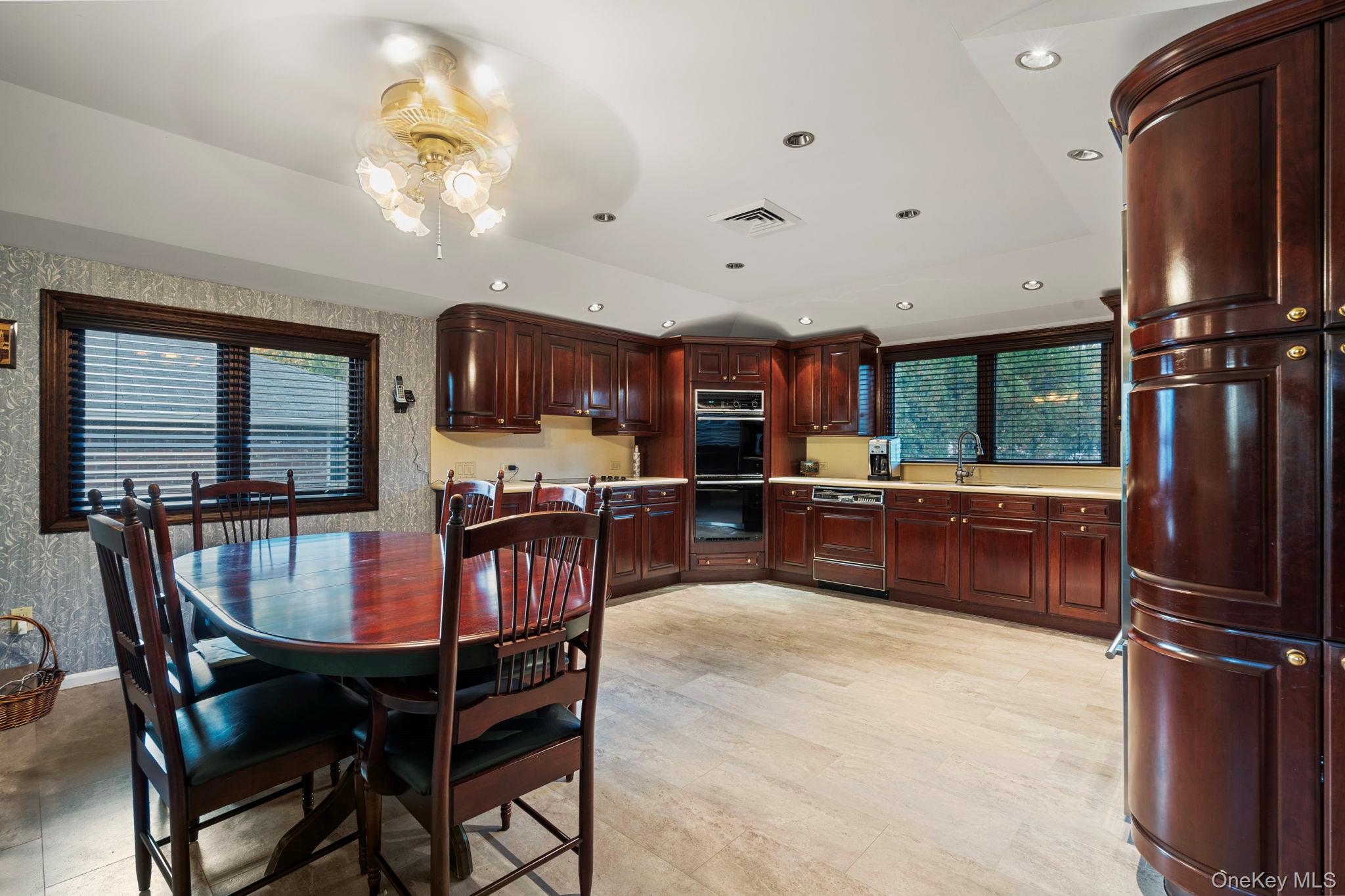 158 Old Courthouse Road Manhasset Hills, NY 11040 - Photo 13 of 47 a kitchen with stainless steel appliances granite countertop a refrigerator a stove a sink a dining table and chairs with wooden floor
