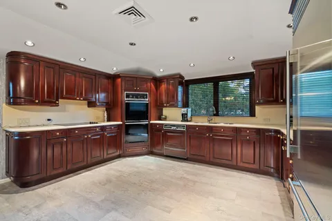a kitchen with wooden cabinets stainless steel appliances a sink and a large window