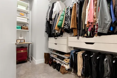 a view of walk in closet with clothes and shoes