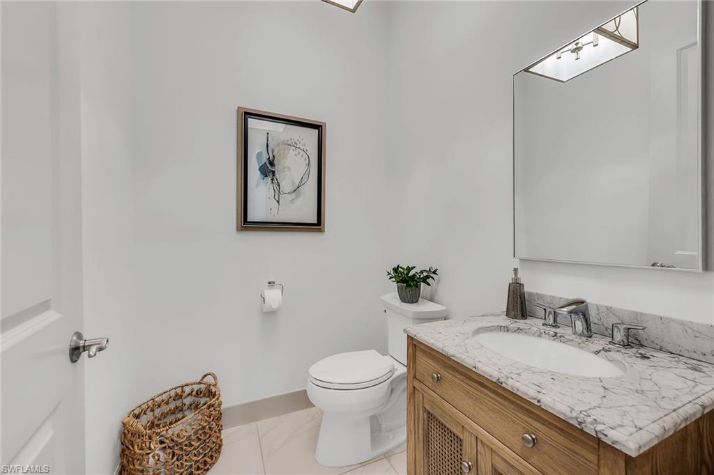 6184 Antigua Way Naples, FL 34113 - Photo 22 of 49 a bathroom with a granite countertop toilet sink and mirror