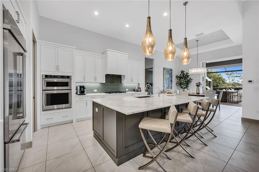 6184 Antigua Way Naples, FL 34113 - Photo 5 of 49 a kitchen with stainless steel appliances kitchen island granite countertop a table chairs and a refrigerator