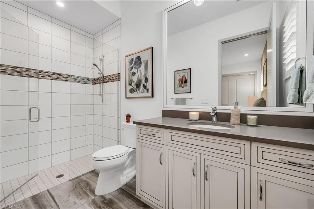 6184 Antigua Way Naples, FL 34113 - Photo 10 of 49 a bathroom with a granite countertop toilet sink and mirror