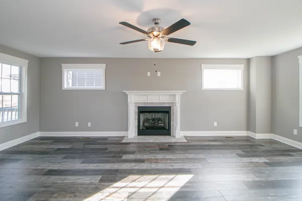 a view of a livingroom with a fireplace a ceiling fan and windows