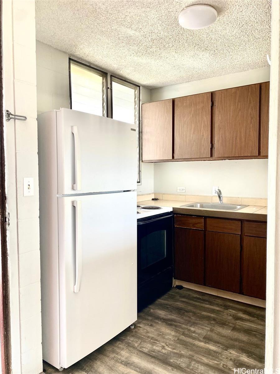 99-70 Kauhale Street, Unit 606 Aiea, HI 96701 - Photo 3 of 8 a kitchen with a refrigerator and a sink