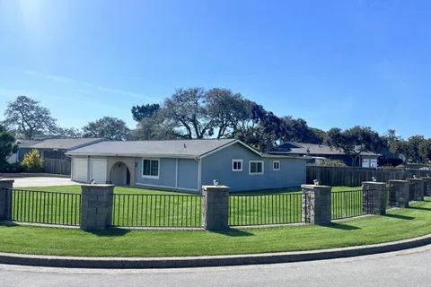 a view of a house with a big yard with plants and large trees