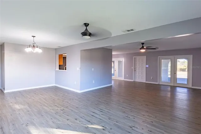 a view of an empty room with wooden floor and a ceiling fan