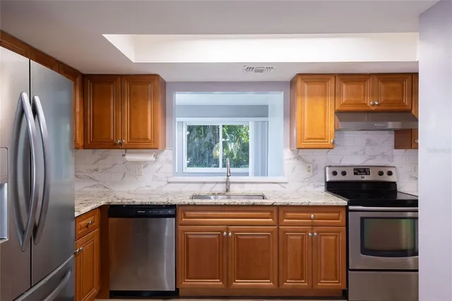 a kitchen with stainless steel appliances granite countertop a sink stove and refrigerator