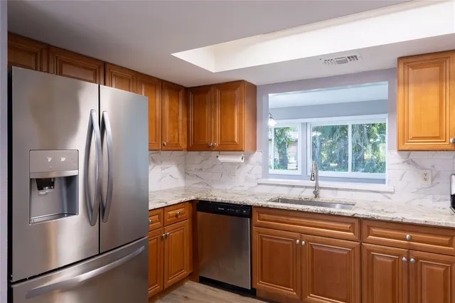 a kitchen with stainless steel appliances granite countertop a refrigerator and a sink