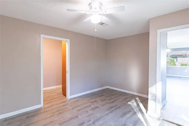 an empty room with wooden floor and a ceiling fan