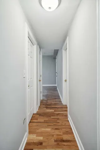 a view of a hallway with wooden floor and a white wall