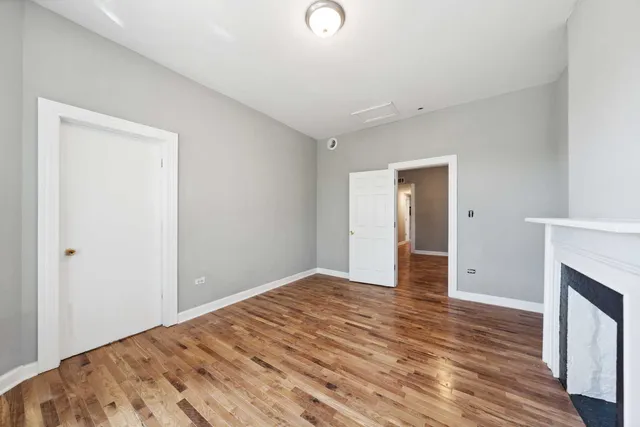 a view of an empty room with wooden floor and a fireplace