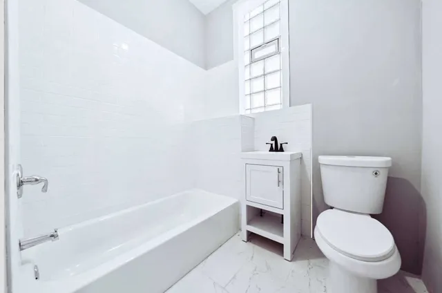 a white toilet sitting next to a bath tub