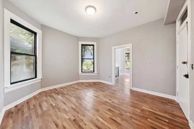 a view of an empty room with window and wooden floor
