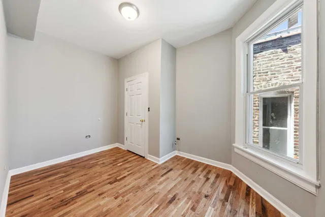 a view of a bedroom with wooden floor and a window