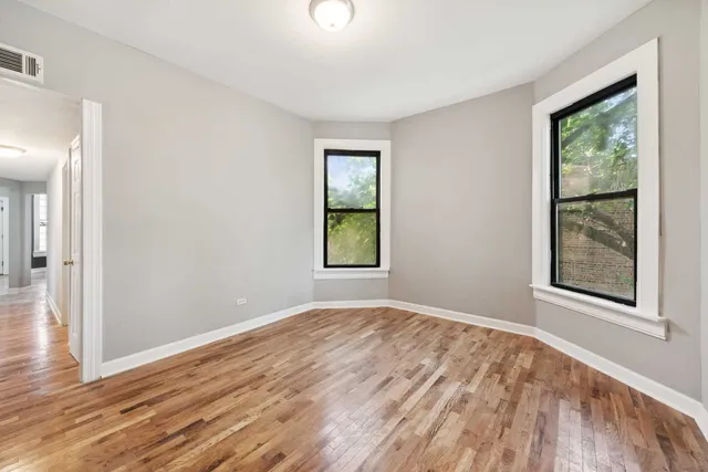 a view of an empty room with window and wooden floor