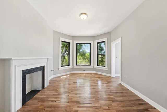 a view of empty room with wooden floor and fireplace