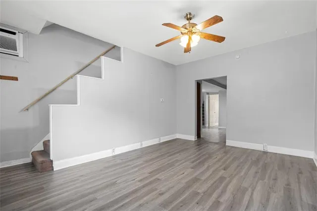 a view of an empty room with wooden floor and a ceiling fan