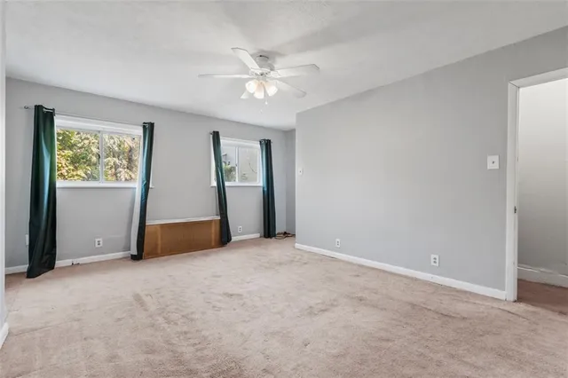 an empty room with fan and windows