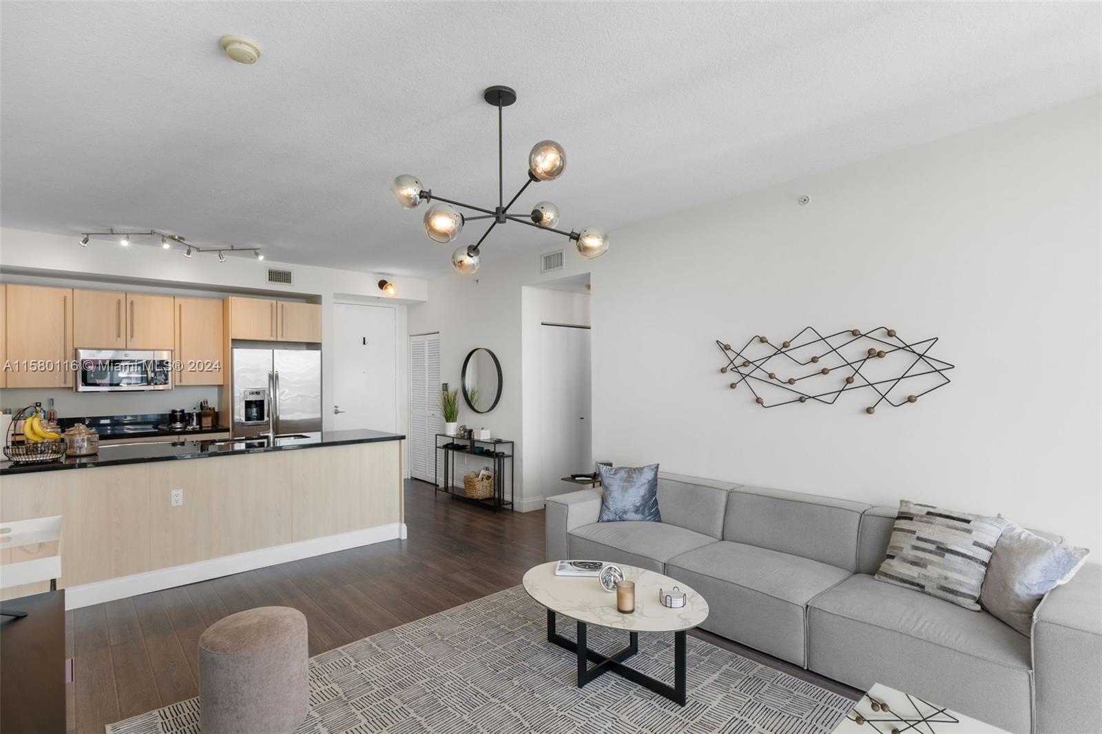 79 Southwest 12th Street, Unit 2204S Miami, FL 33130 - Photo 11 of 40 a living room with furniture kitchen view and a chandelier