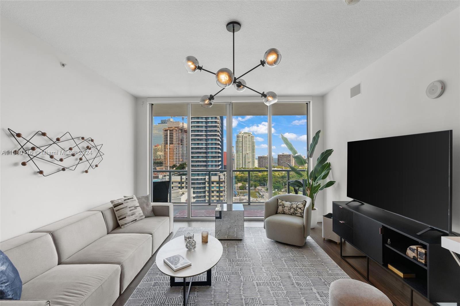 79 Southwest 12th Street, Unit 2204S Miami, FL 33130 - Photo 7 of 40 a living room with furniture a chandelier and a flat screen tv