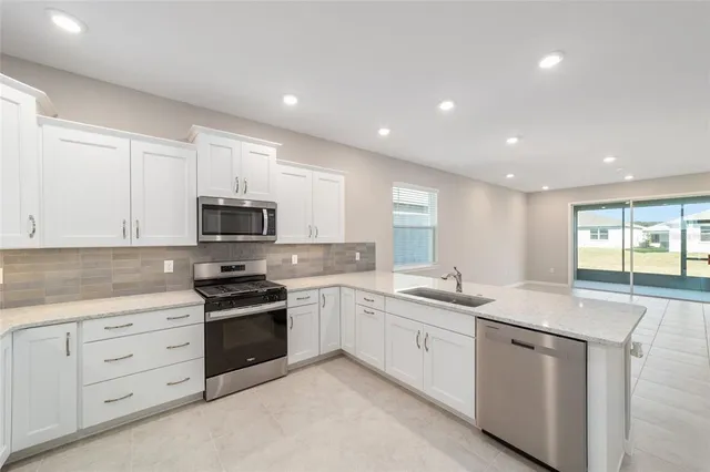 a kitchen with stainless steel appliances granite countertop a sink and dishwasher a stove top oven with white countertops