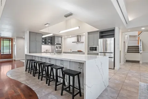 a kitchen with stainless steel appliances kitchen island granite countertop a dining table chairs and a refrigerator